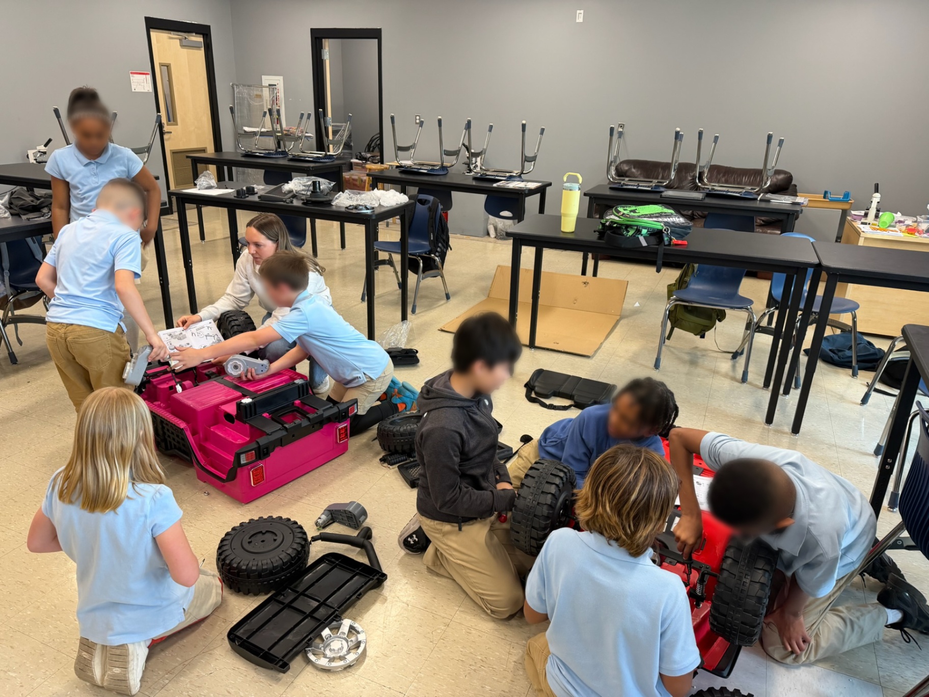 Wide view of students disassembling ride-on cars in a science classroom
