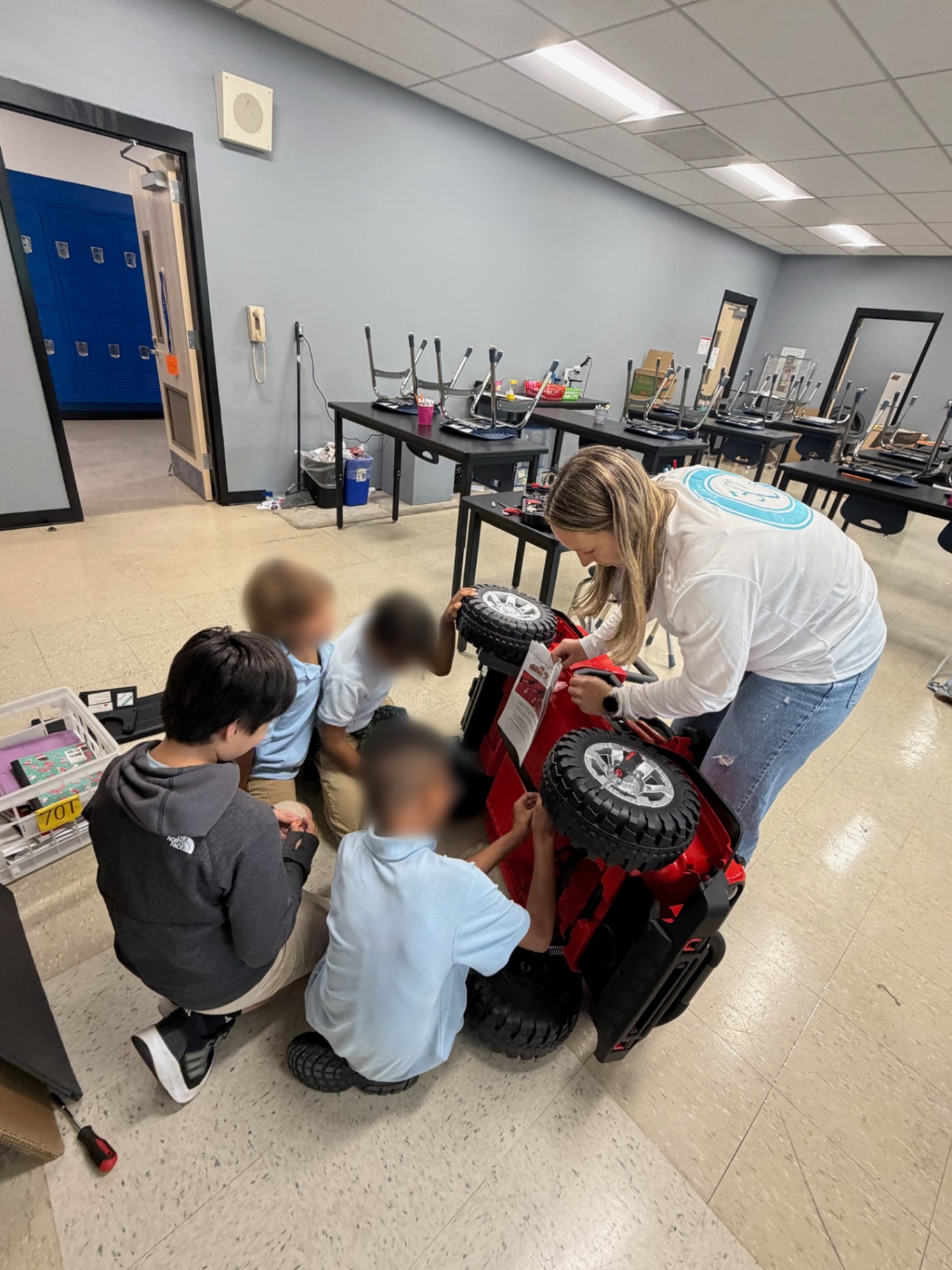 Mentor and students assembling wheels on a red adaptive Jeep