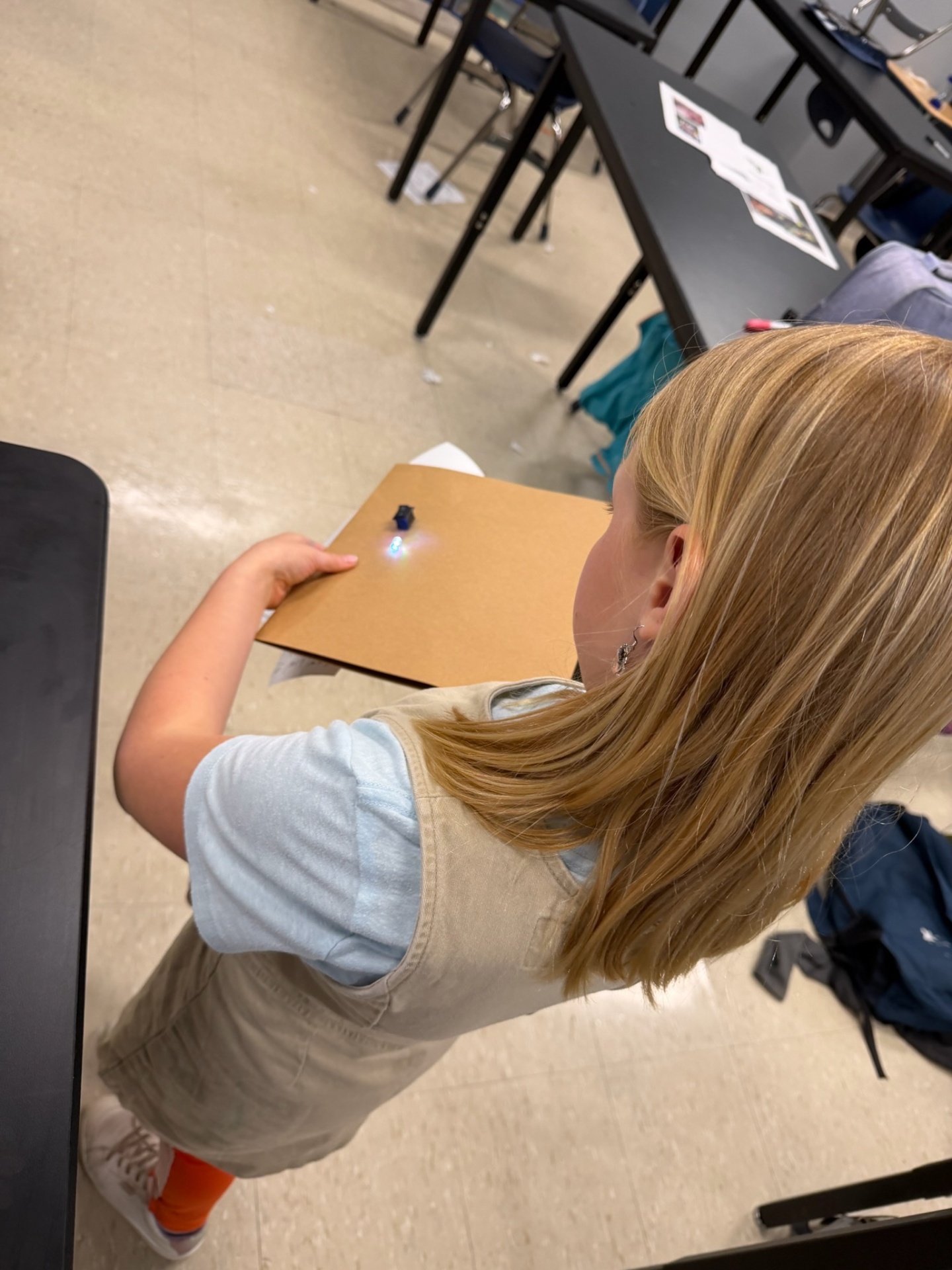 Young student experimenting with a small LED circuit on cardboard