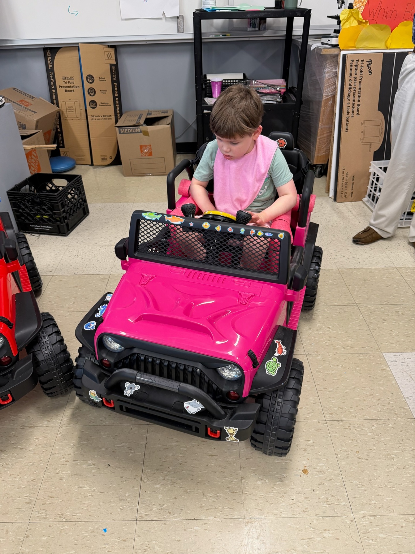A young child seated in a finished pink adaptive Jeep decorated with stickers