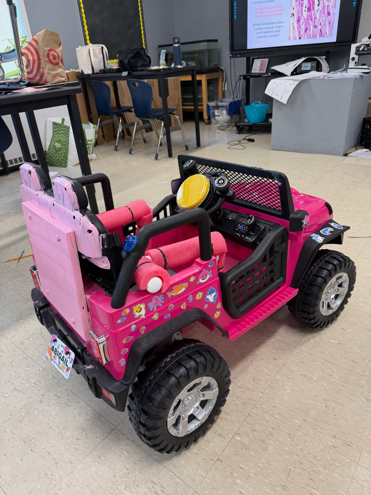 Rear view of a completed pink adaptive Jeep with foam supports and Abigail's license plate
