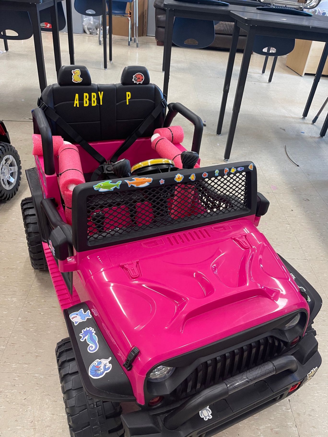 Top-down view of a completed pink adaptive Jeep with 'Abby' embroidered on the seat