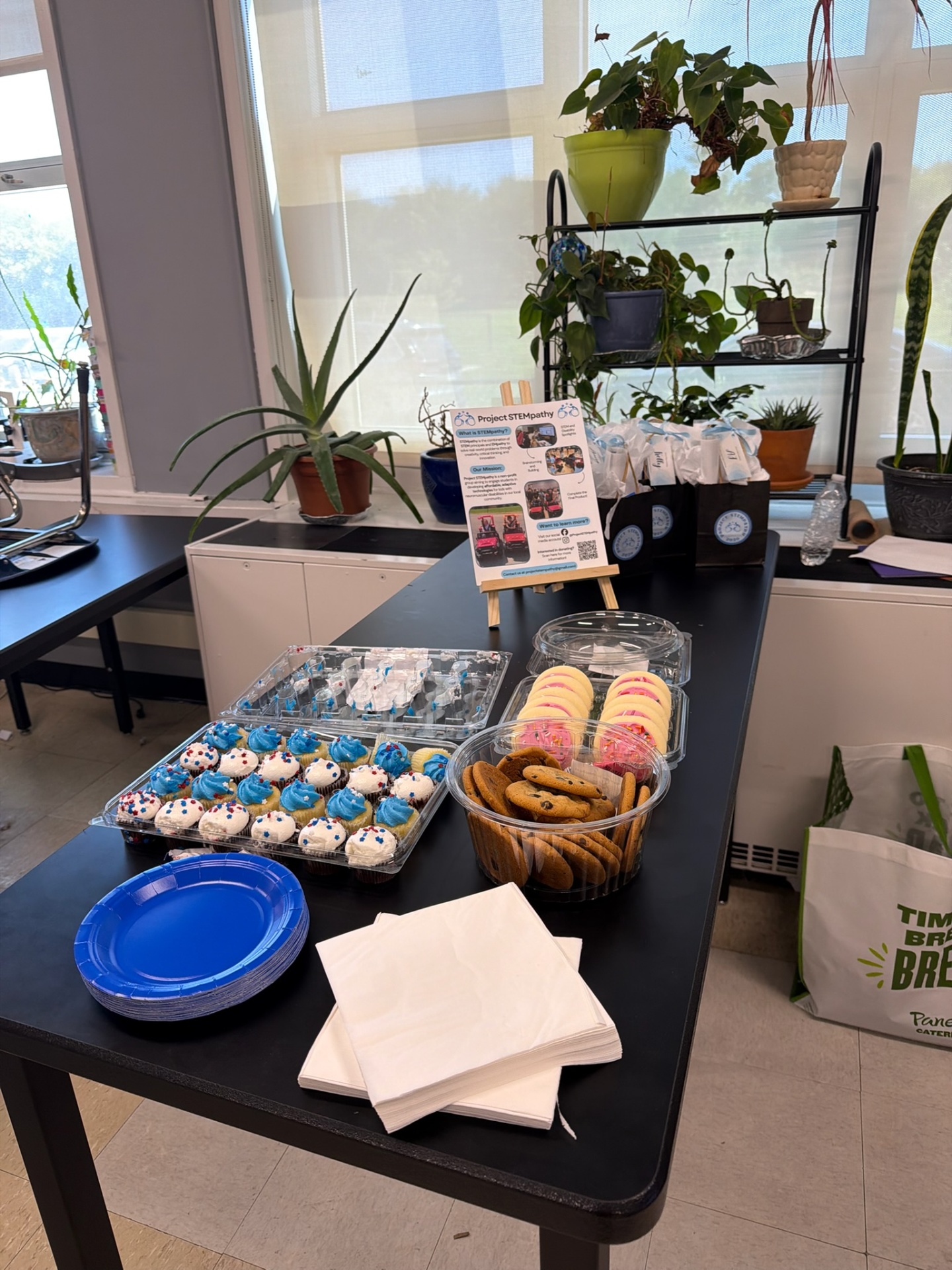 Project STEMpathy event table with cupcakes, cookies, and an informational display board