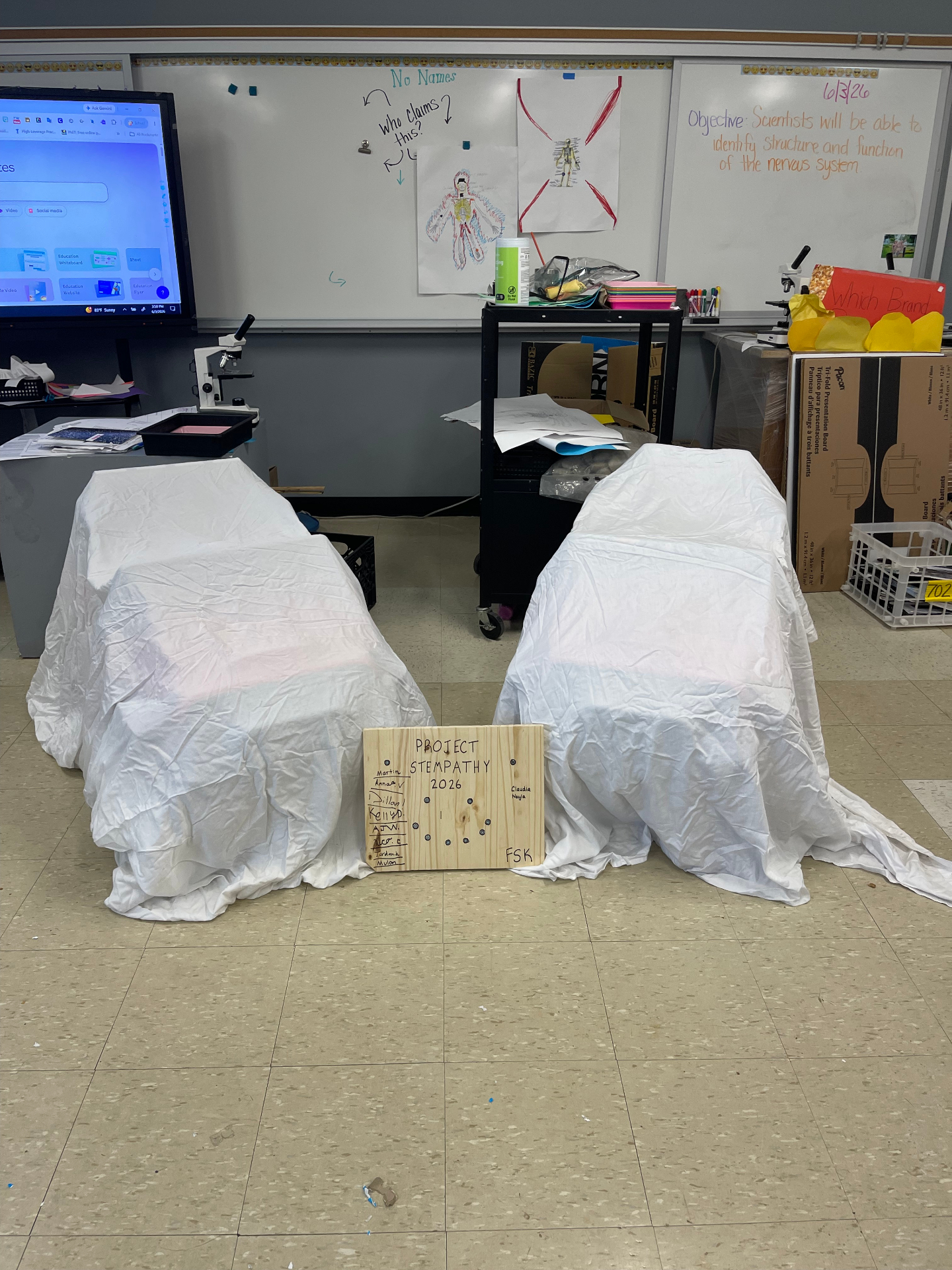 Two ride-on cars covered with white sheets before a classroom reveal