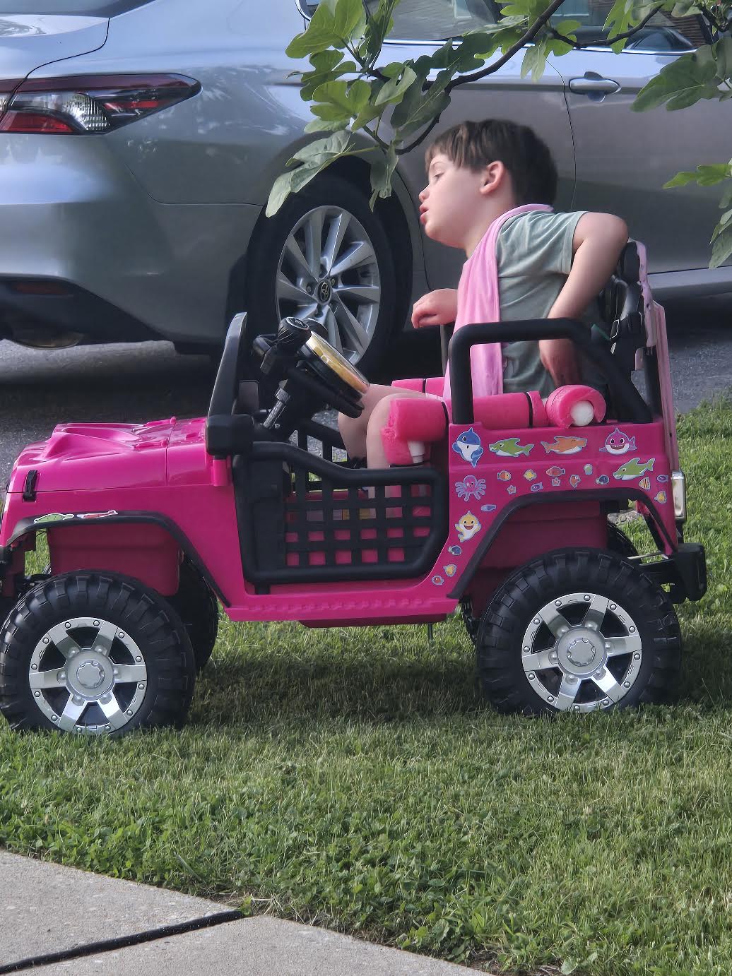 A young child enjoying a ride in a custom pink adaptive Jeep